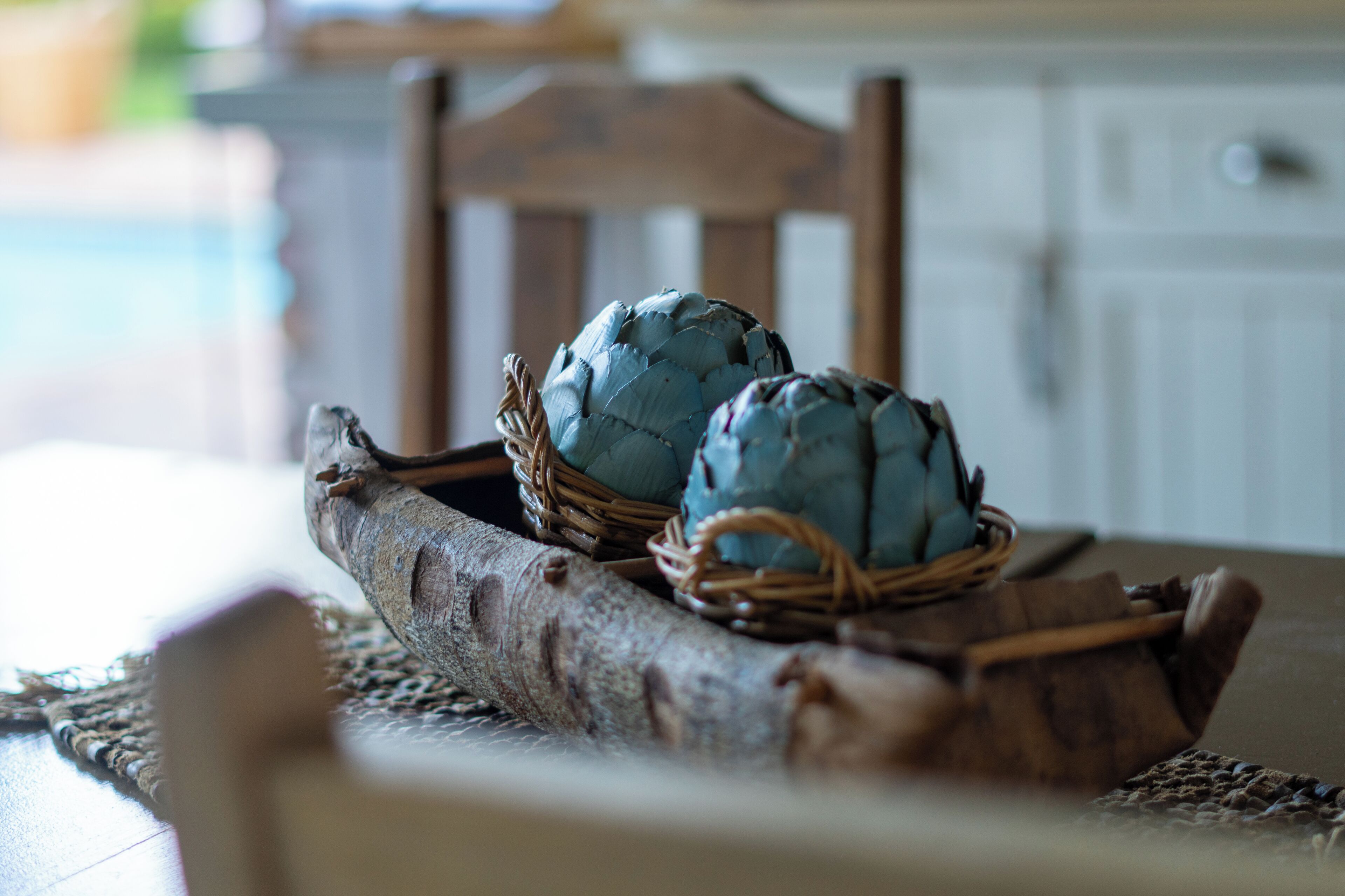 Two artichokes in wicker baskets on a wooden table.