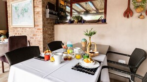 Une table de petit-déjeuner dressée avec différents plats, des boissons et une carte accrochée au mur.