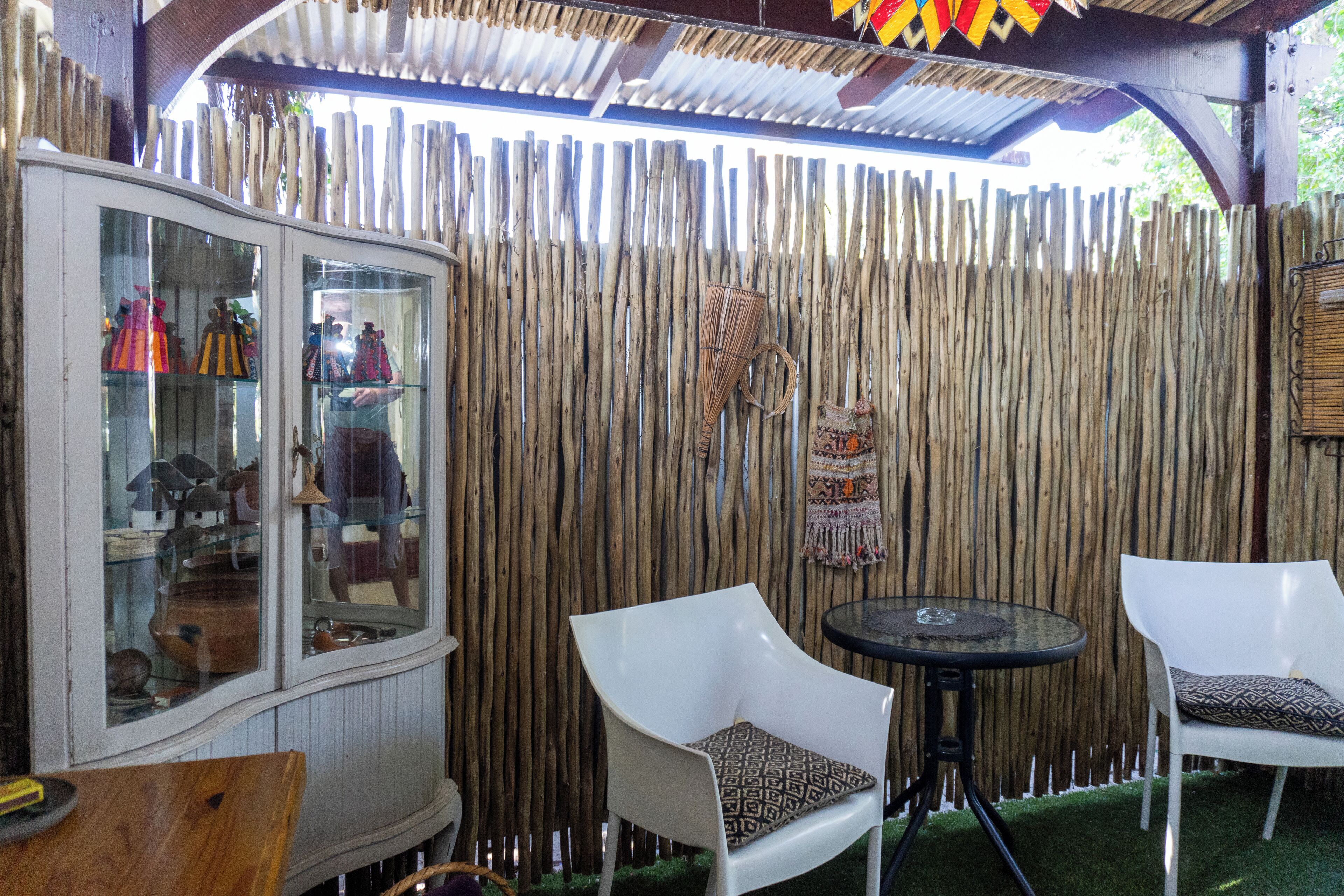 A wooden fence, a glass cabinet with items, and two white chairs with cushions.