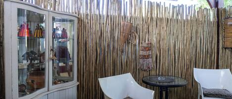 A wooden fence, a glass cabinet with items, and two white chairs with cushions.