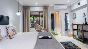 Une chambre à coucher comprenant un lit, une chaise, une table et donnant sur un jardin.