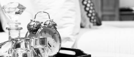 A tray with a diamond-shaped object, a clock, and several glasses on a bed.