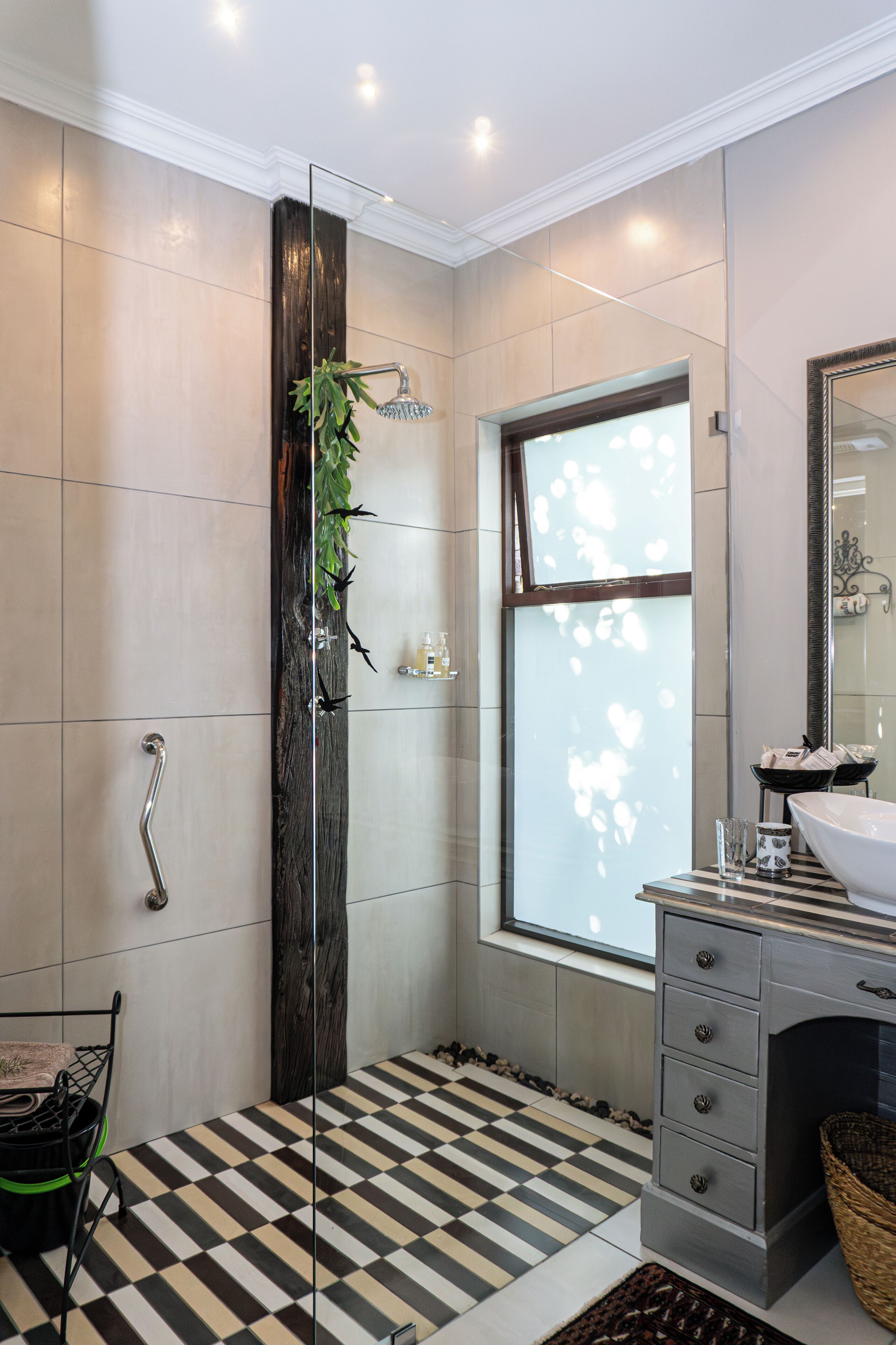 Un bany modern amb una cabina de dutxa de vidre, una finestra gran i un terra de pissos.
