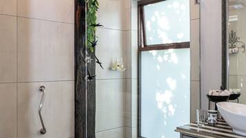 Un bany modern amb una cabina de dutxa de vidre, una finestra gran i un terra de pissos.