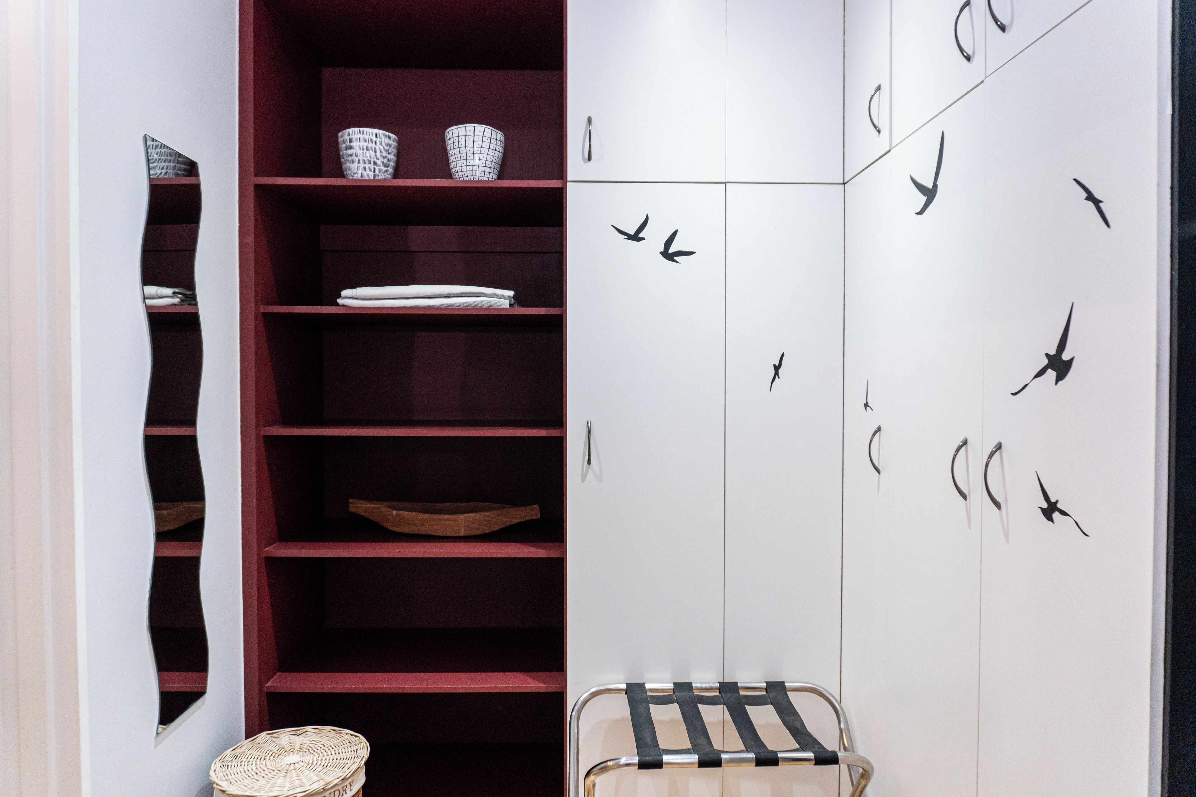 A room with a wardrobe, shelves, and a chair.
