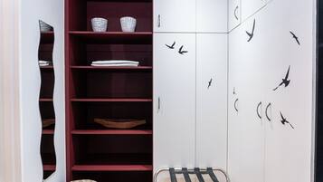 A room with a wardrobe, shelves, and a chair.