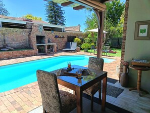 A backyard with a swimming pool, a barbecue area, and outdoor furniture. - Earthbound B&B (Oudtshoorn)