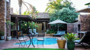 Un jardin avec une piscine, des chaises longues et un espace patio couvert.