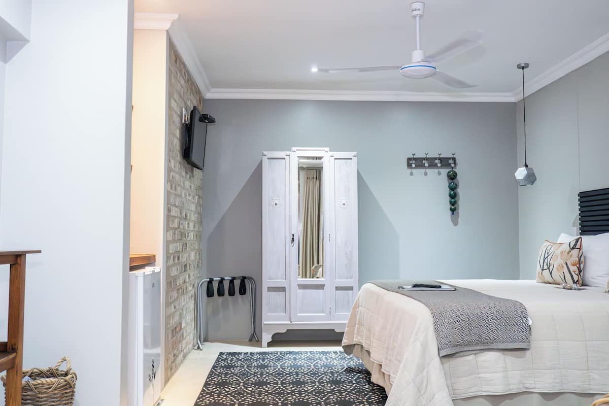 A bedroom with a bed, a wardrobe, a ceiling fan, a radiator, and a patterned rug.