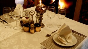 A dining table set with wine glasses, plates, cutlery, and a candle.