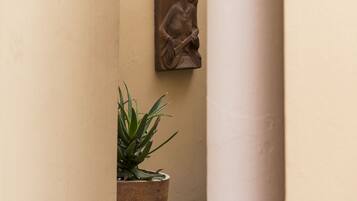 A potted plant with a stone sculpture on a wall.