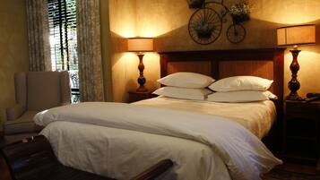 A neatly made bed with white linens, two bedside lamps, a chair, and a wall-mounted bicycle decoration.
