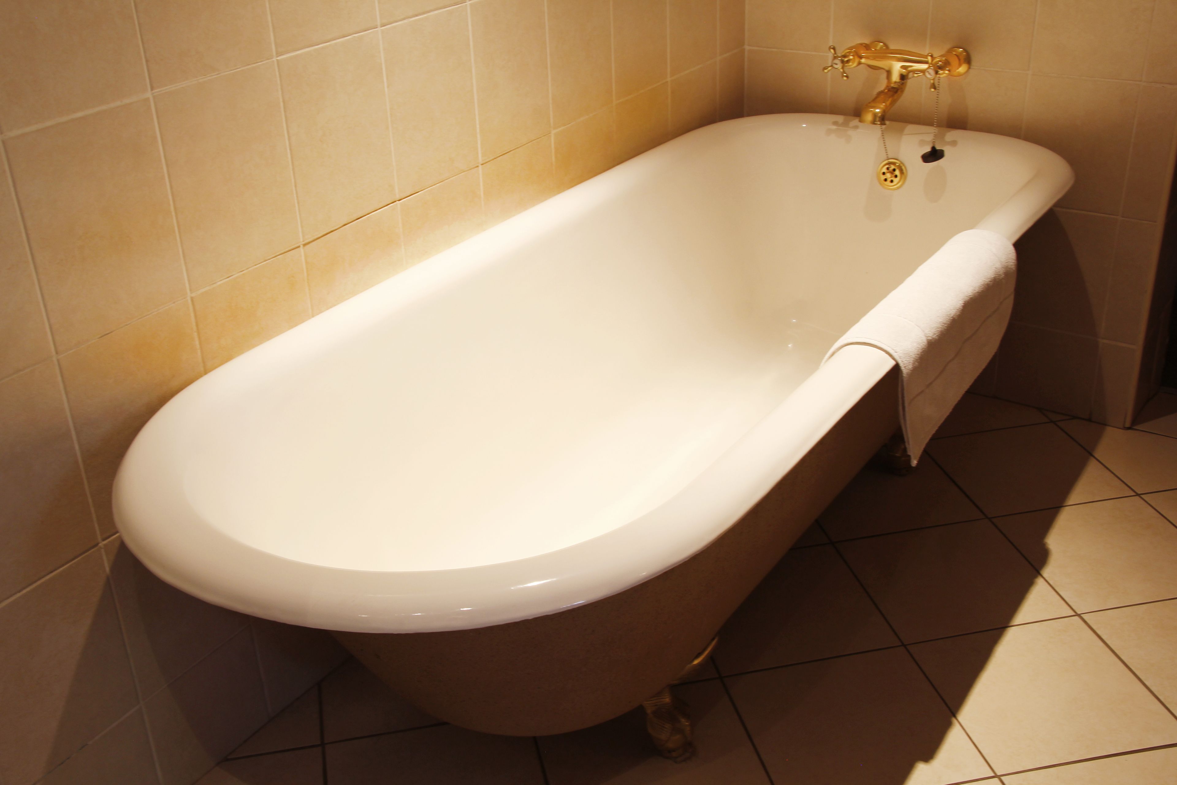 Eine freistehende Badewanne in einem Badezimmer mit beigen Fliesen.