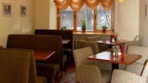 A restaurant with booths and tables, warm lighting, and a window with curtains. - Jakob Lenz Guesthouse (Riga)