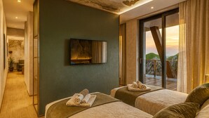 A hotel room with two beds, a television mounted on the wall, and a balcony with a view of the landscape. - Degenija Boutique Hotel & Spa (Rakovica)