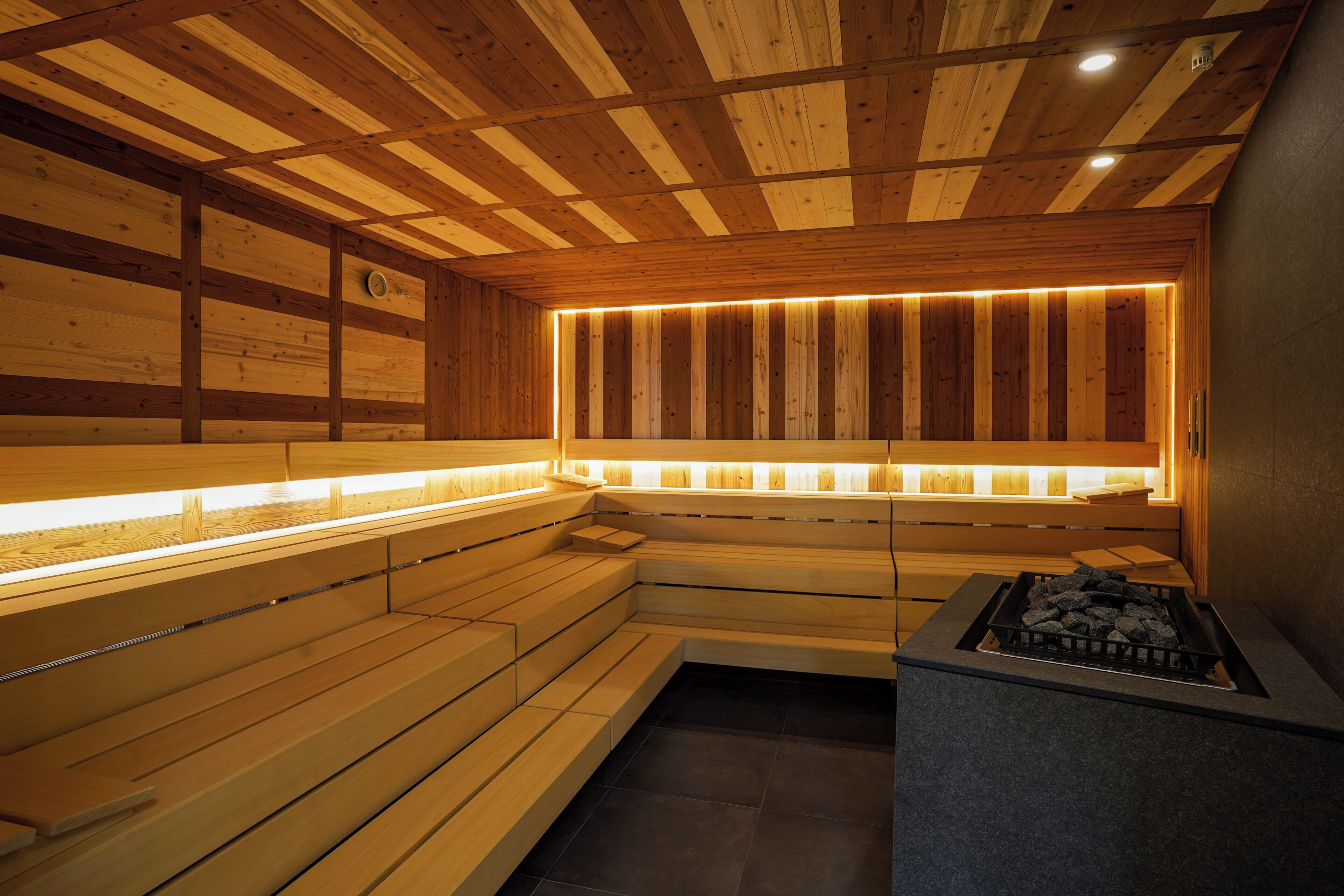 Un sauna en bois, doté de bancs et d’un foyer intégré.