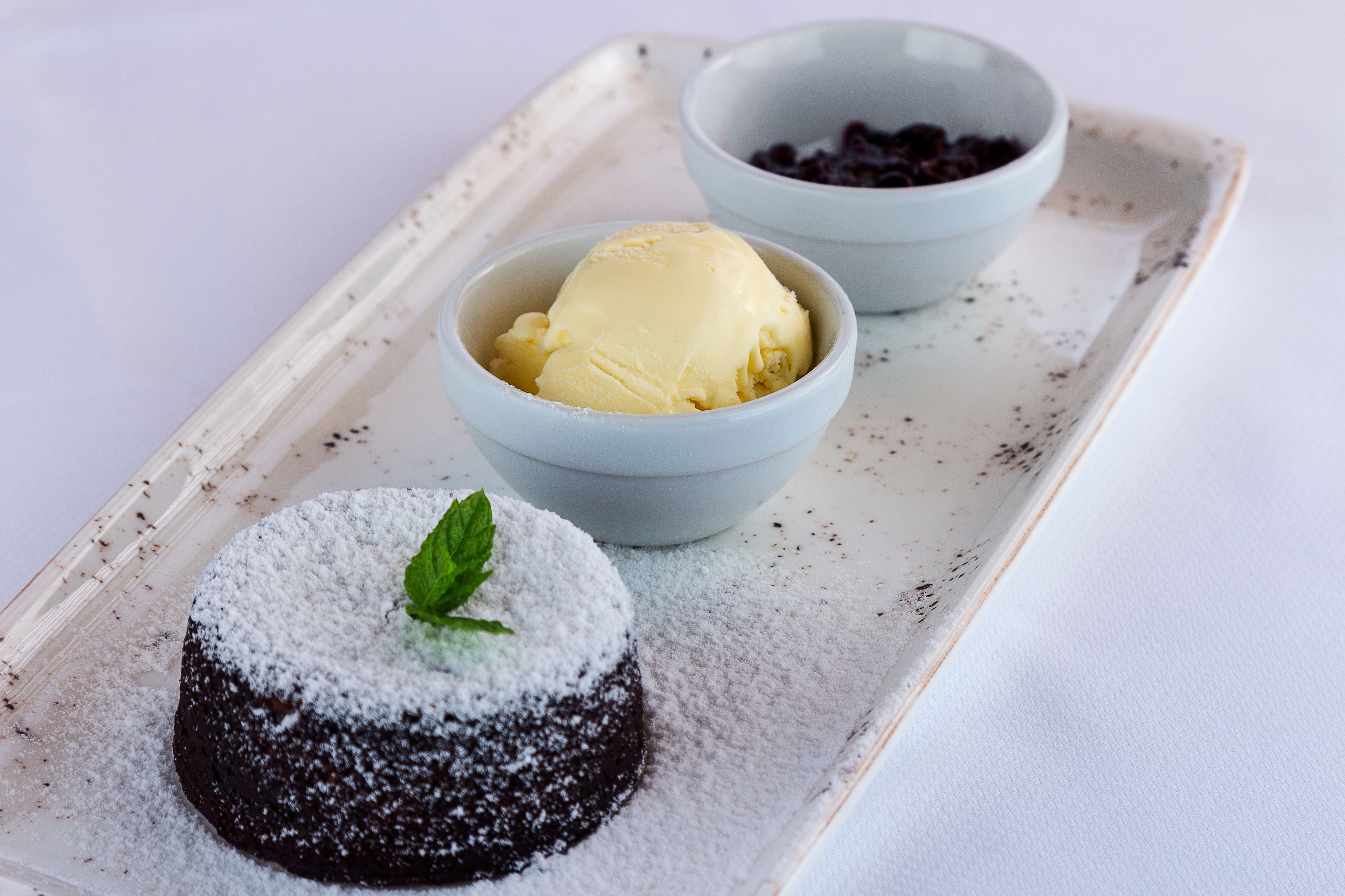 Ein Dessertteller mit einem Schokoladen-Lava-Kuchen und zwei Eisbechern.