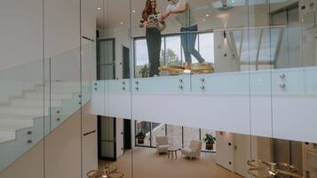 A modern interior with glass railings, a staircase, and a seating area with a view.