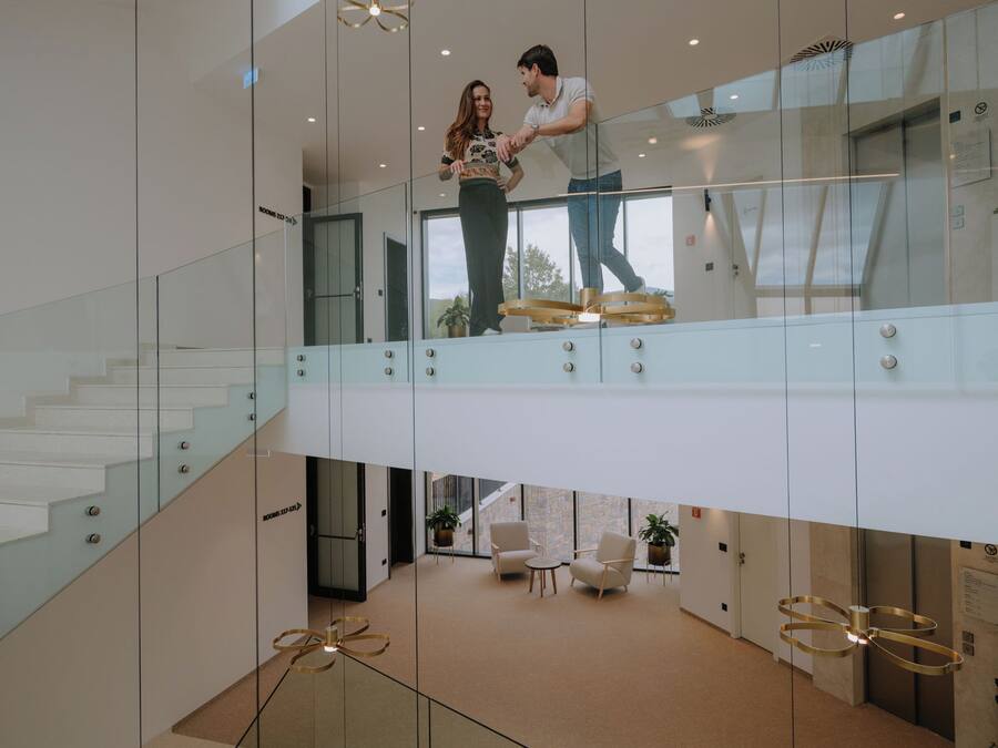 A modern interior with glass railings, a staircase, and a seating area with a view.