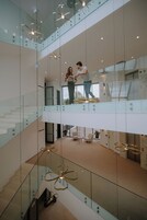 Un interior moderno con barandillas de vidrio, una escalera y una zona de estar con vistas.