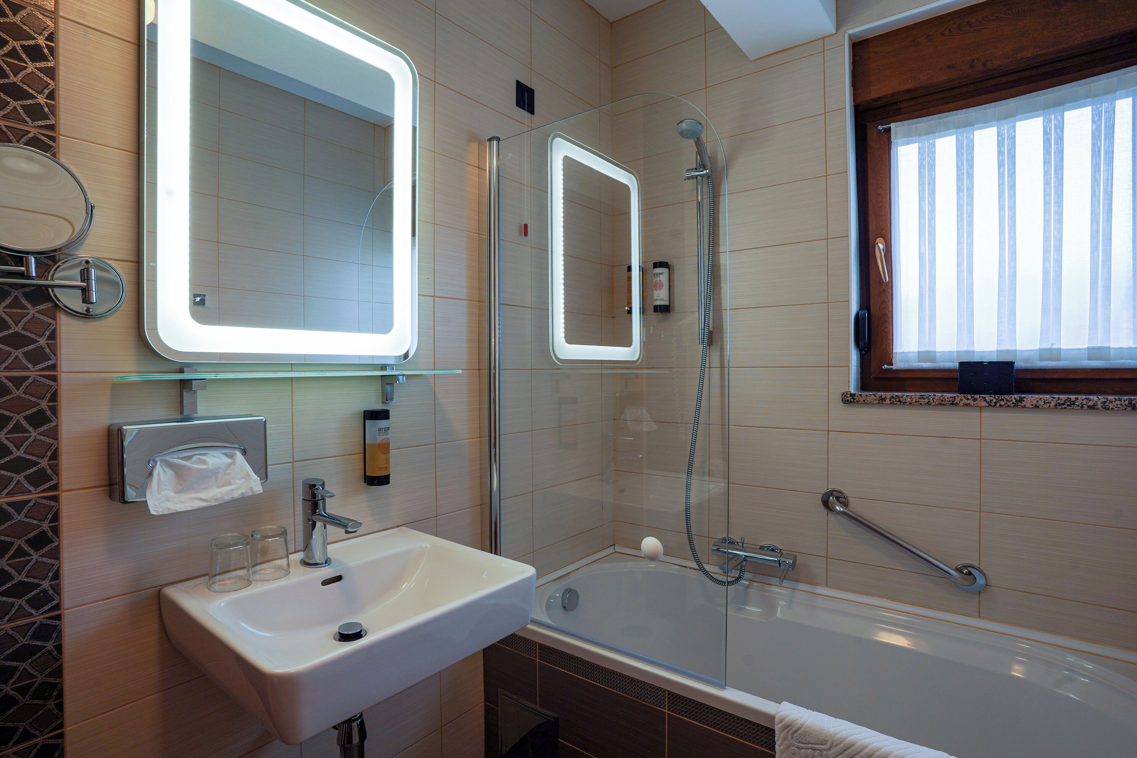 A modern bathroom with a large mirror, a sink, a bathtub, and a shower.