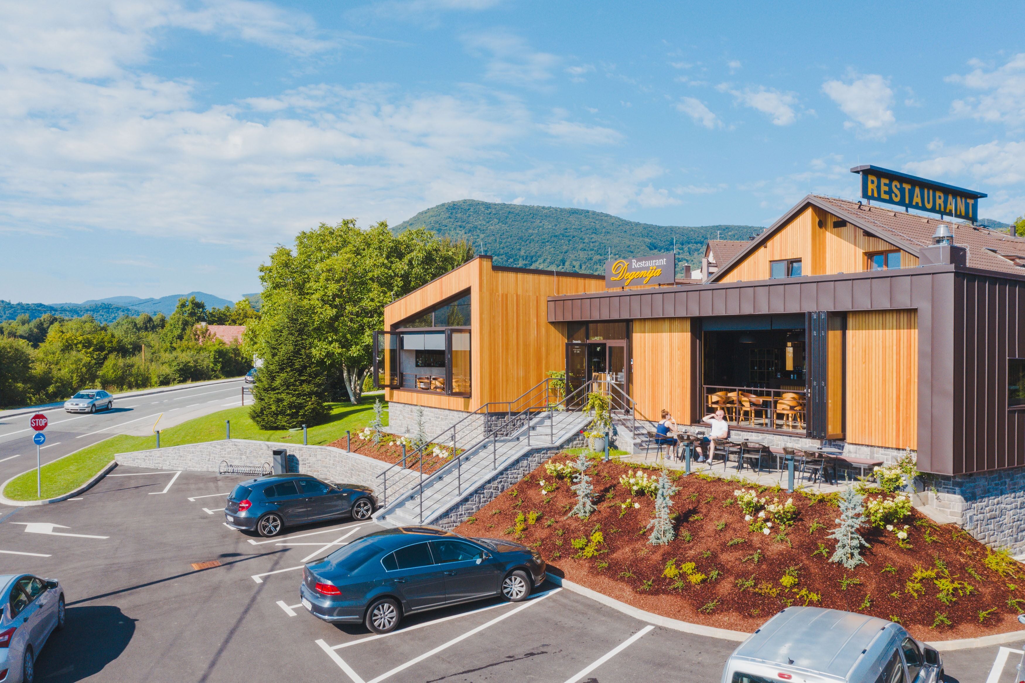 Ein modernes Restaurant mit Holzausside, Außenbereich und Parkplatz.