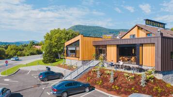 Ein modernes Restaurant mit Holzausside, Außenbereich und Parkplatz.