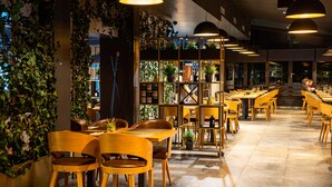 A restaurant with wooden tables and chairs, a plant-covered wall, and pendant lighting. - Degenija Boutique Hotel & Spa (Rakovica)