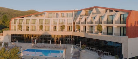 Um hotel moderno com piscina, área de estar externa e vista para as colinas ao redor.