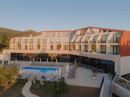 Un hotel moderno con piscina, zona de estar al aire libre y vistas a las colinas circundantes.
