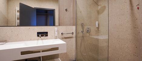 A modern bathroom with a glass-enclosed shower, a white sink with a towel rack, and a mirror above the sink.