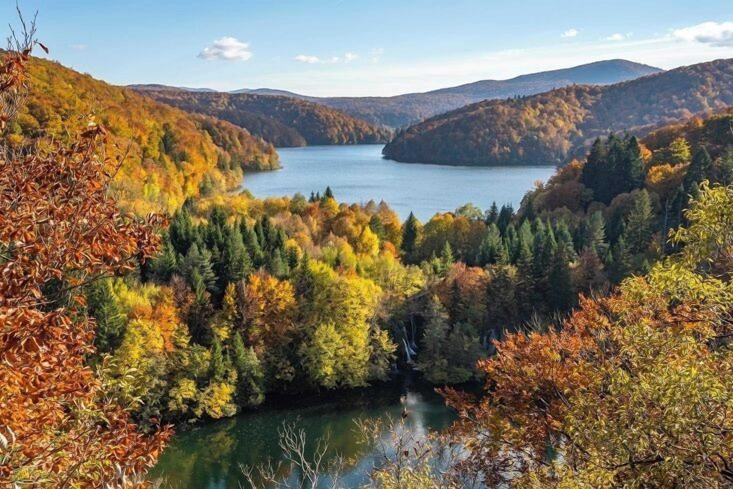 A lake surrounded by autumn-colored trees and hills.