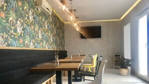 A restaurant interior with a patterned wall, wooden tables, and a mix of modern and classic chairs. - Hotel Vettonia (Merida)