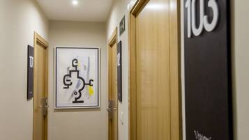 A hallway with doors labeled 101 and 103, a framed abstract artwork, and a sign with the number 103.