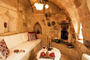 Una habitación con paredes de piedra, un sofá blanco, una mesa con velas y una chimenea.