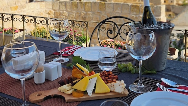 An outdoor dining setup with a view of a historic town and a prominent rock formation. - Hezen Cave Hotel (Ürgüp)