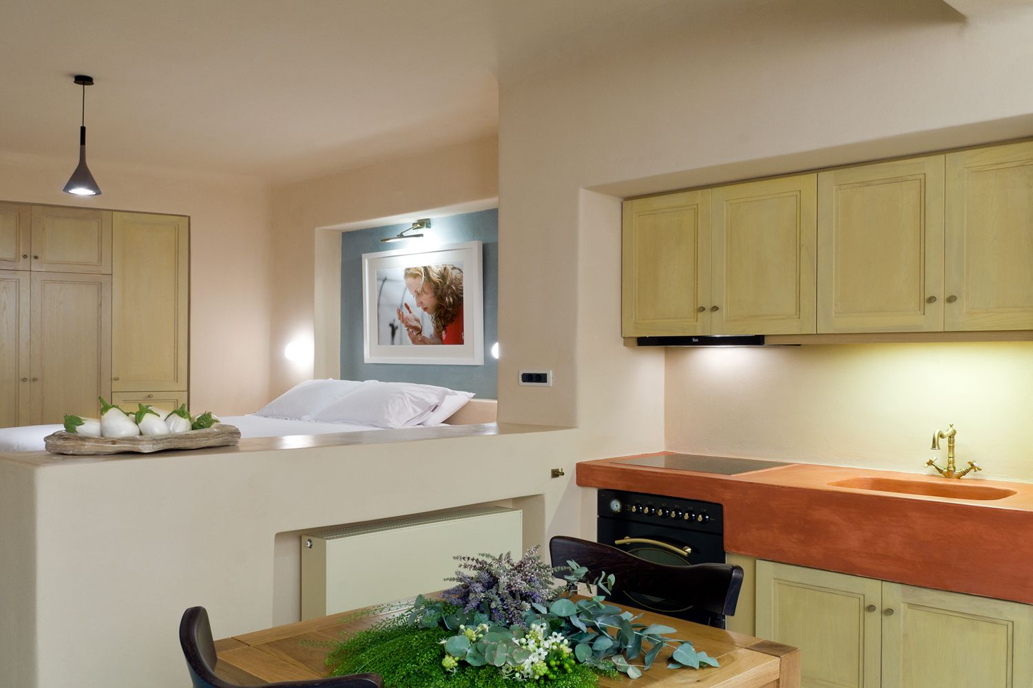 A compact kitchen with a built-in oven, a sink with a gold faucet, and a dining area with a wooden table and chairs.