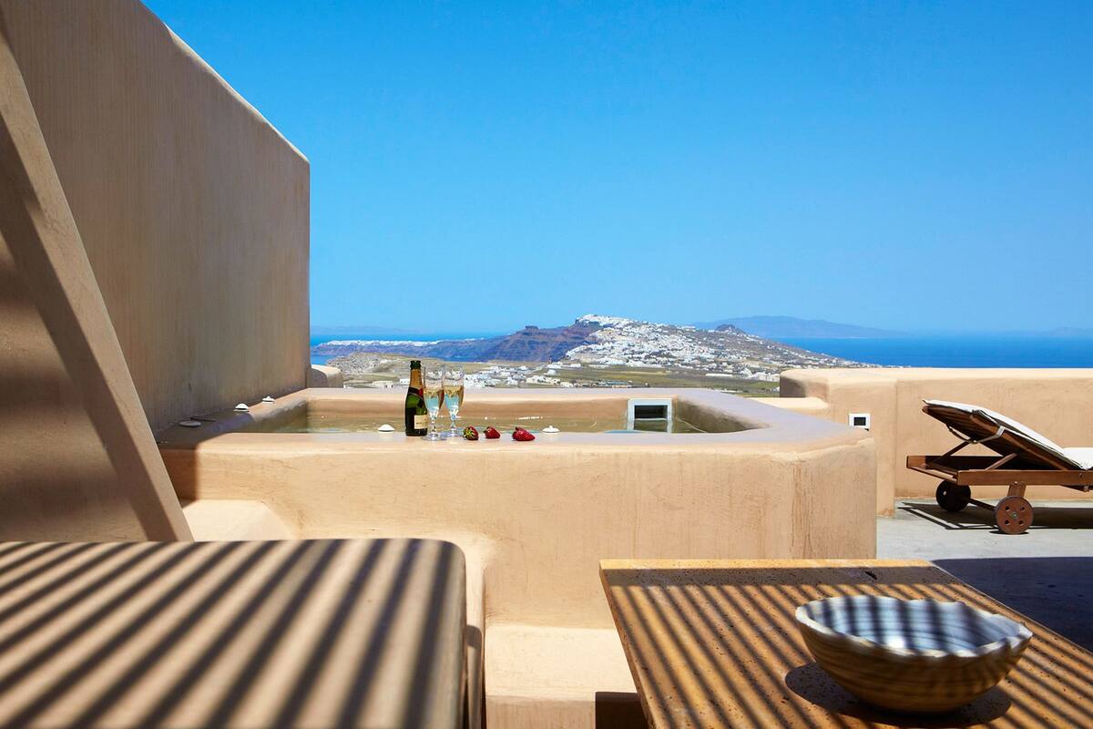 Eine Terrasse mit Meerblick, eine Champagnerflasche und ein Tisch mit einer Schüssel.