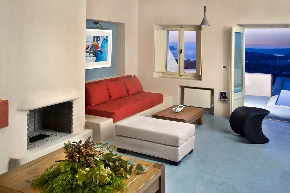 Ein modernes Wohnzimmer mit Kamin, rotem Sofa und Blick auf die Stadt im Abenddämmerung.