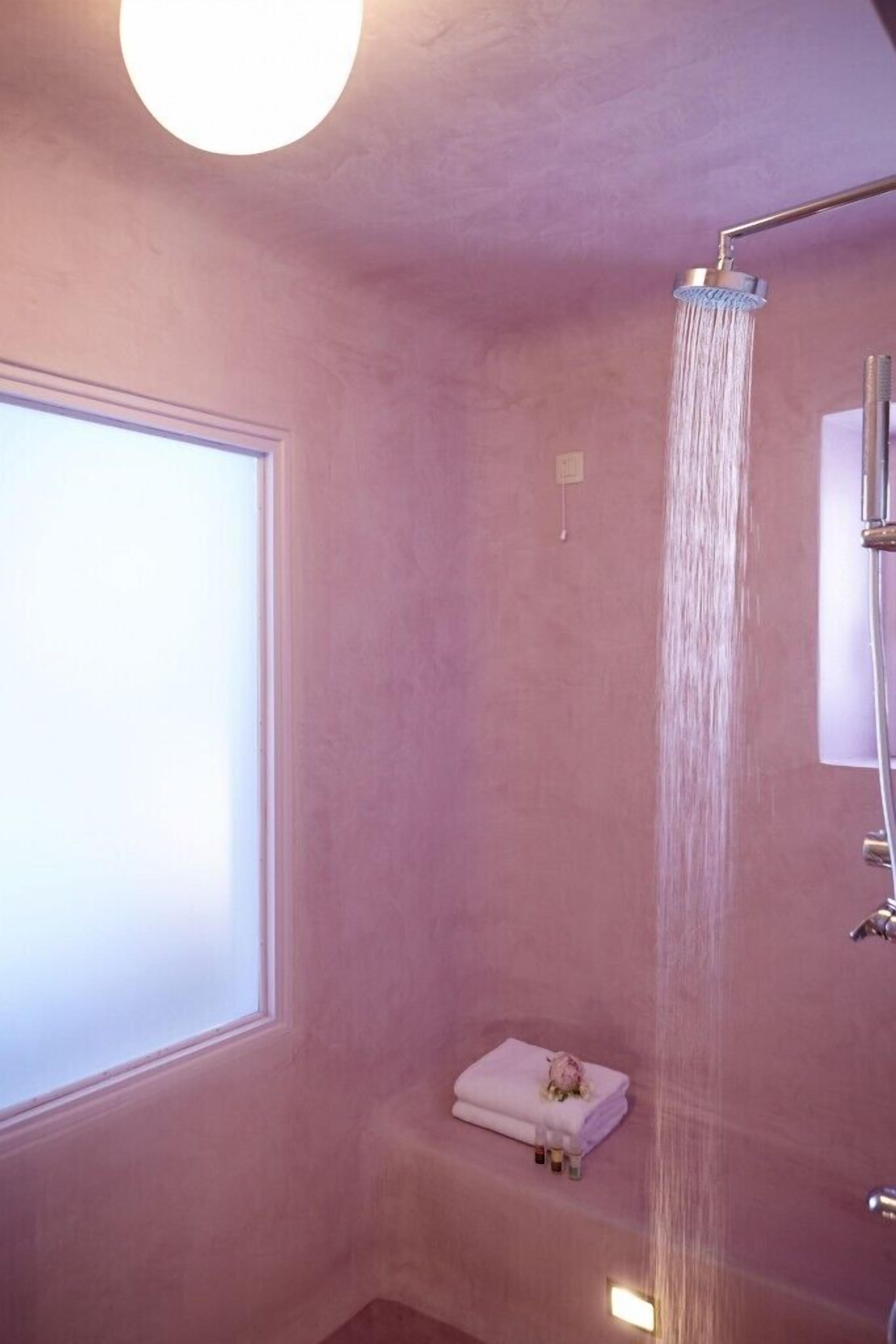 A bathroom with a shower, a window, and a towel rack with a folded towel.