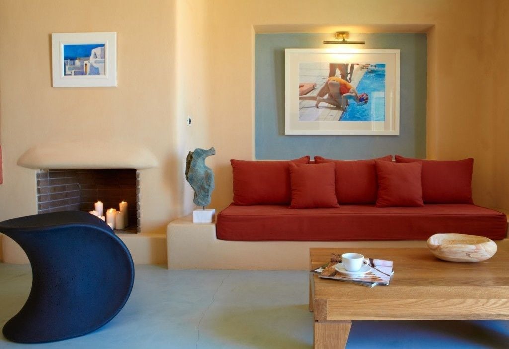 Un salon avec un canapé rouge, un fauteuil bleu, une table basse en bois et une cheminée.
