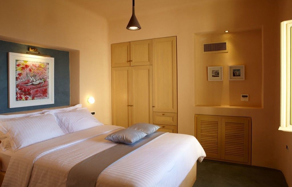 A bedroom with a bed, a wardrobe, a painting, and a window.