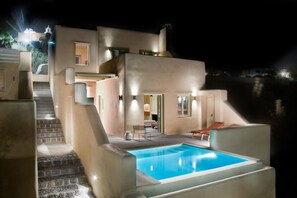 Una villa moderna con piscina, escalera y zona exterior bien iluminada.