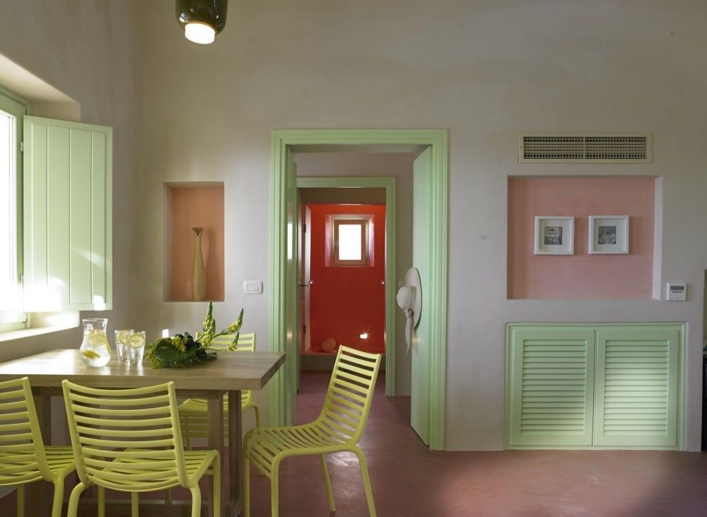 A dining area with a table, chairs, and a red door in the background.