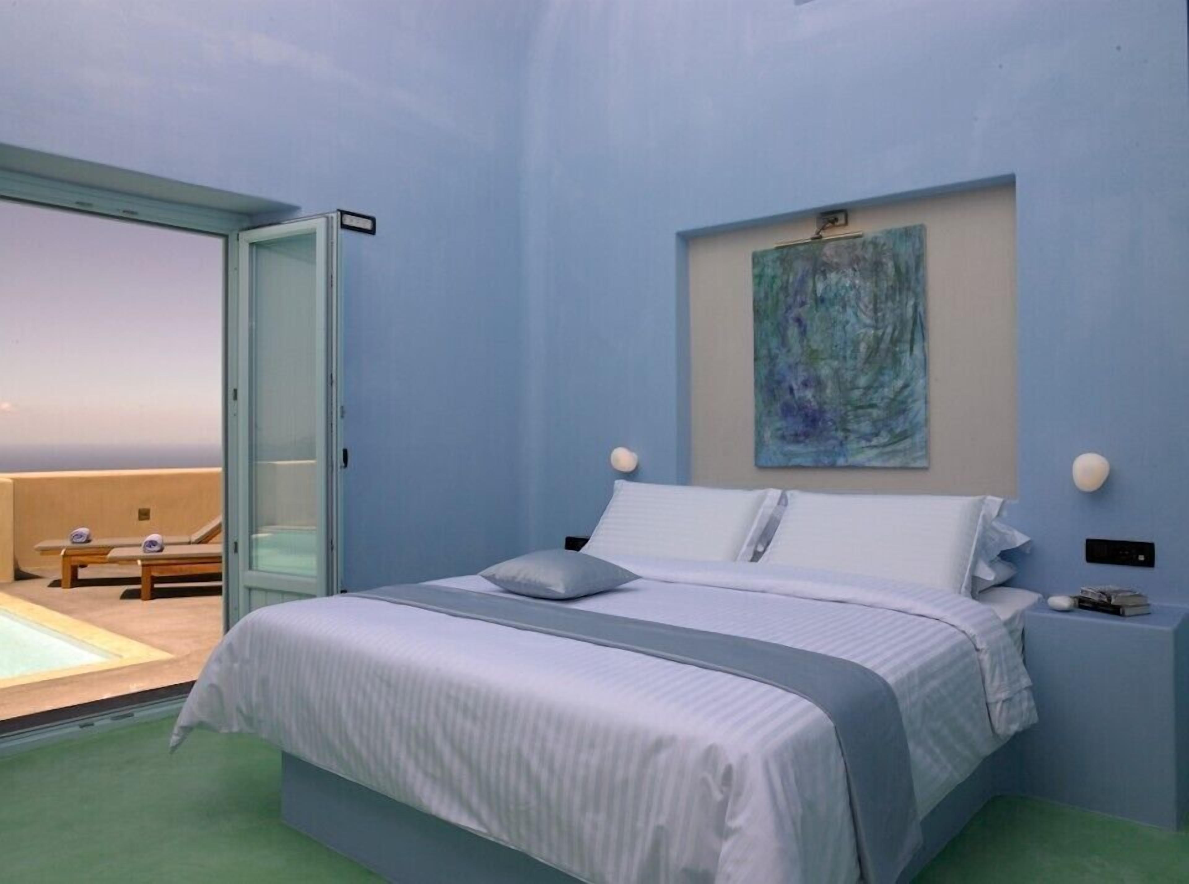 A bedroom with a bed, a painting, and a view of a pool area.