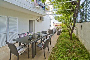 An outdoor patio with a glass-top table, wicker chairs, and a small potted plant.