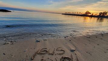 A beach with footprints and the word "SUS" and "de VOLI" written in the sand.