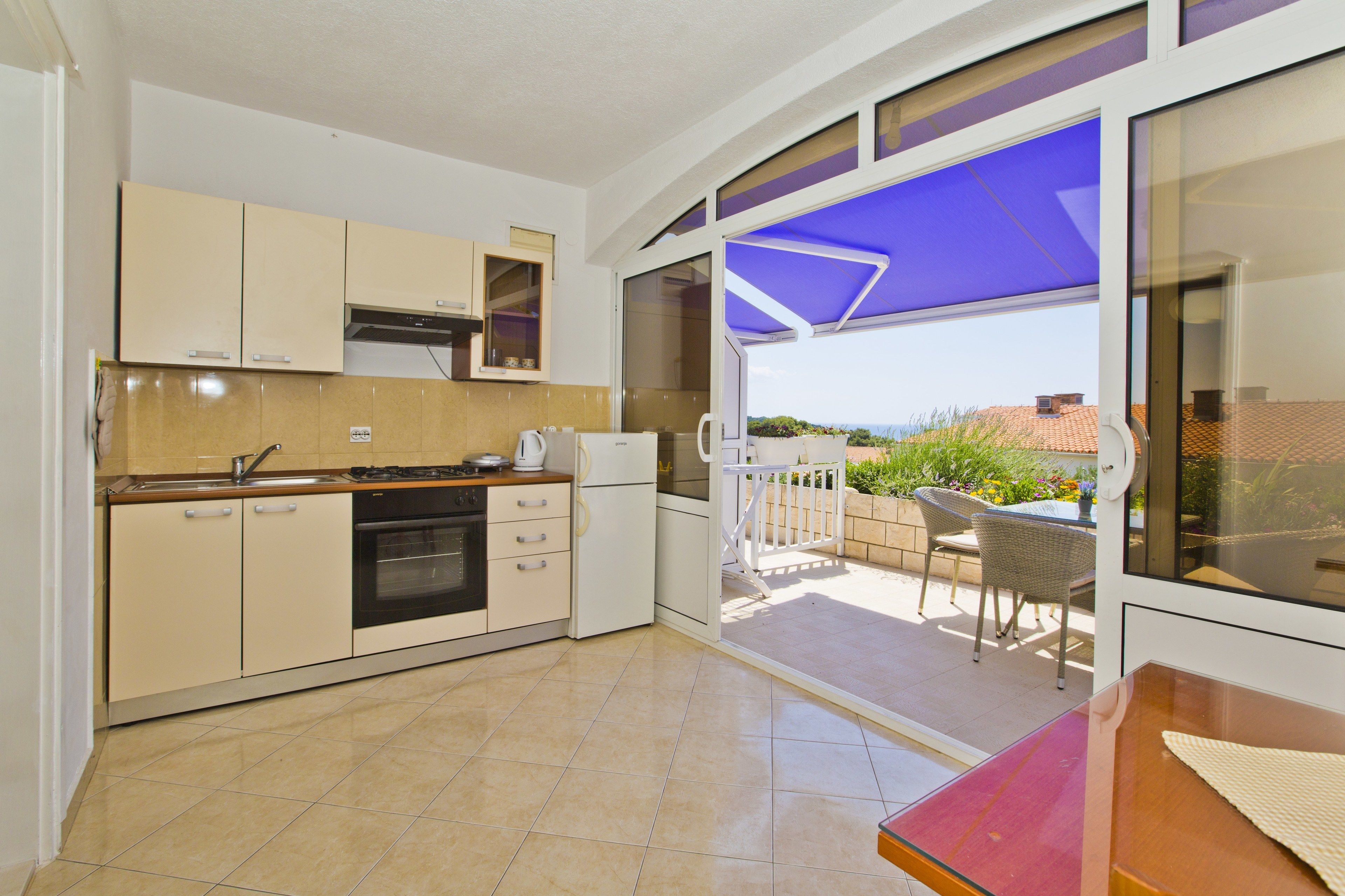 A kitchen with a dining area, a view of the garden, and a sliding glass door leading to the patio.