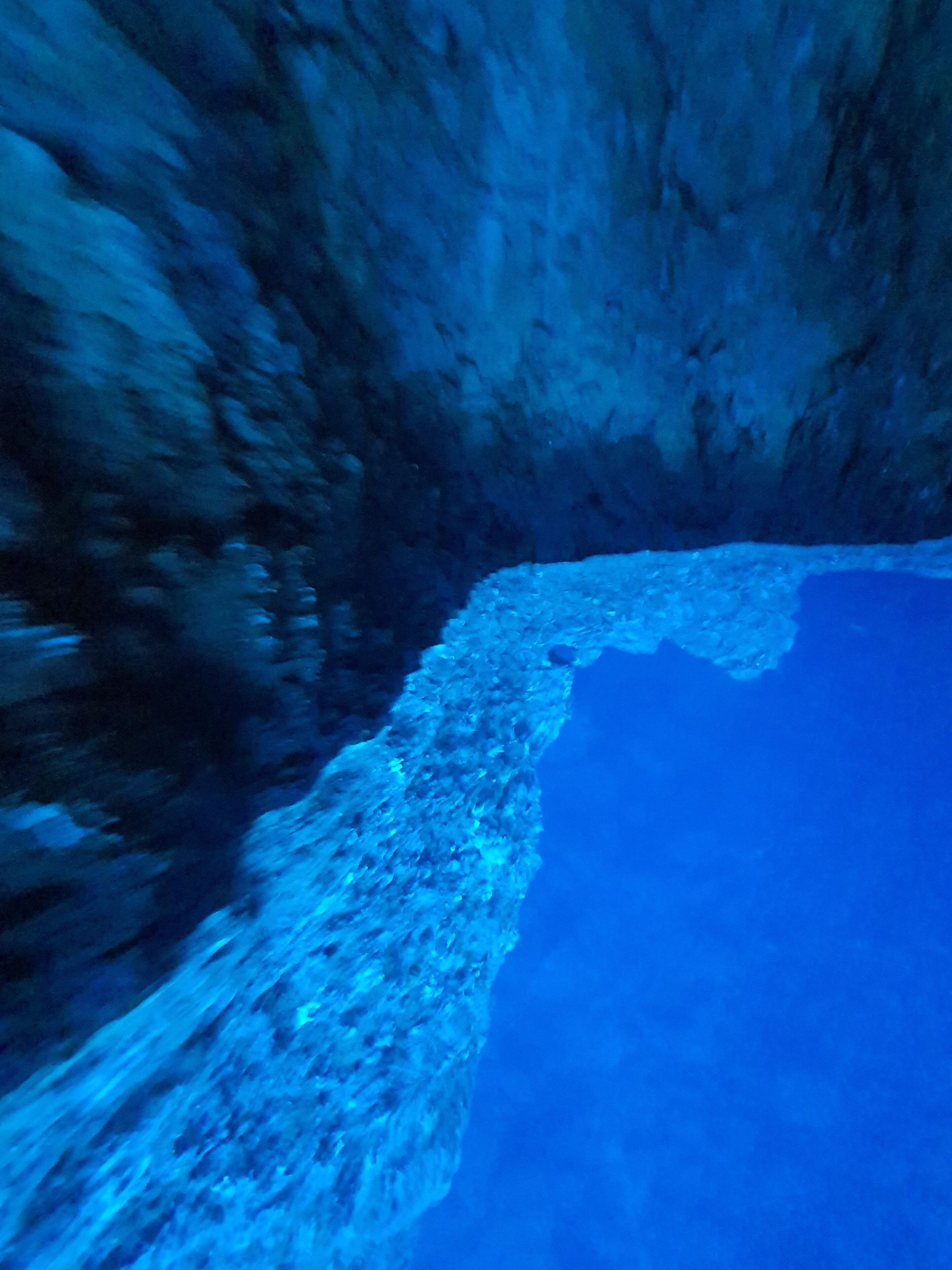 Une grotte sous-marine avec une corniche rocheuse et une eau d’un bleu cristallin.