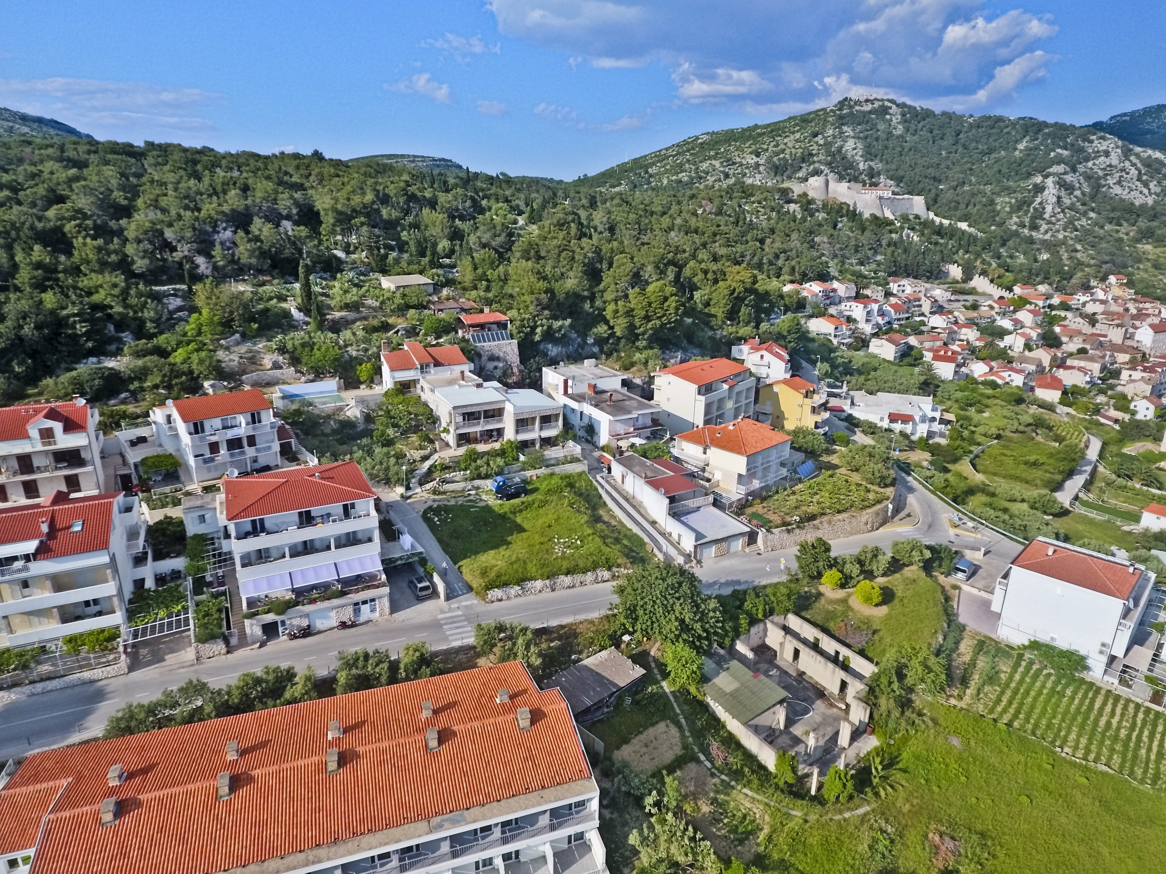 A residential area with multi-story buildings, a central road, and surrounding greenery.